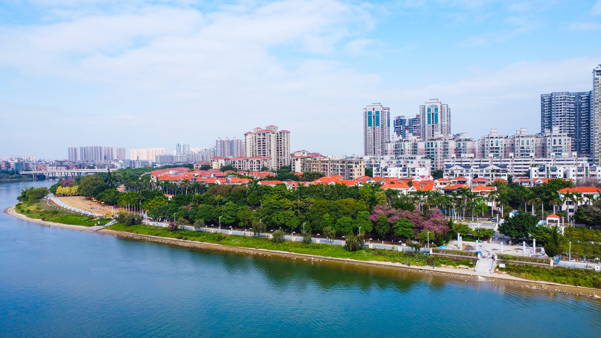 漫步在东莞石龙金沙湾公园碧道上,湛蓝天空与大片绿植相互映衬,江边